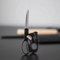 Black-handled scissors on a reflective surface with a blurred background