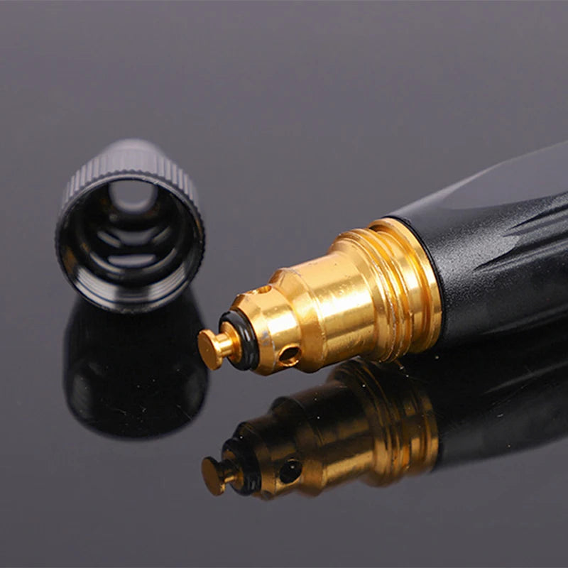 Black and gold tattoo machine pen on a reflective gray surface