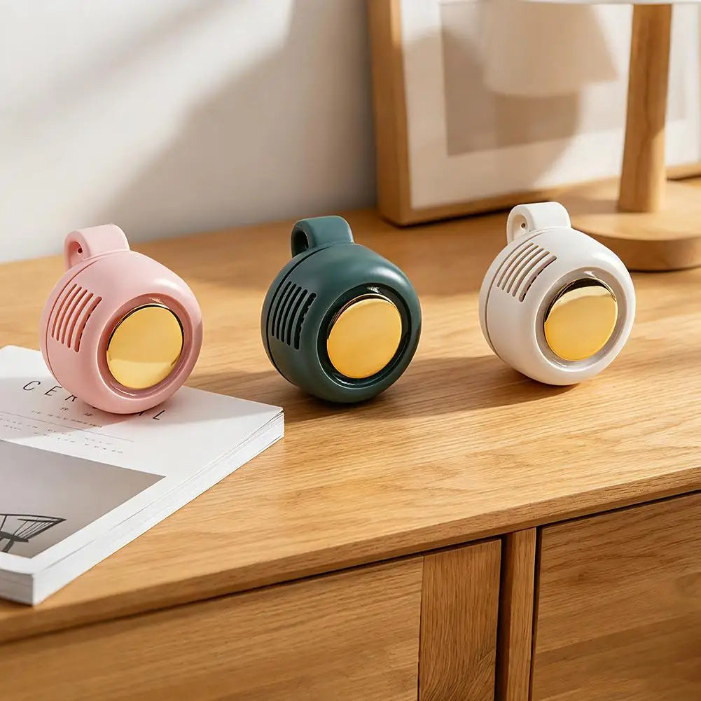Three small round speakers in pink, green, and white on a wooden surface.